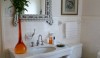 The attention grabbing Venetian style mirror is just grand enough for this space. The tall orange container with flowers from the garden is a complimentary color to the deep toned towels on the opposite side of the room.