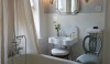 Opposite the fireplace is a long footed tub with a mirrored glass tub table for the proverbial glass of champagne. The small scale double circle back perching chair is both decorative and useful.