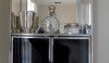 A close up of the cabinet with black glass doors and silver and glass objects to make the cabinet sparkle.