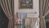 The corner of a bath with old textiles and a repurposed teapot for flowers. A soft and flattering color on the walls and a touch of blue.  A quiet and relaxing space.