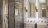 master bathroom Beautiful, layered silver travertine is rich and elegant and looks particularly good with nickel fittings. The small fireplace is not visible in this photo but adds warmth and charm to this great space with with useful accessories like a small table and bench. The tall slab baseboards add some drama to the room and the proportion of the medicine cabinets makes the room feel very tall.