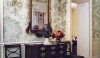 30 The front hall of a grand New York features enriched architectural doorways painted a soft cream and beautiful painted panels of a damask pattern. The scale of the mirror and the rich mahogany of the chest creates an updated but traditional entry great for entertaining and greeting guests.