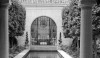 Classicism at its best. The arched doorway is framed by matching columns and topiary evergreens.